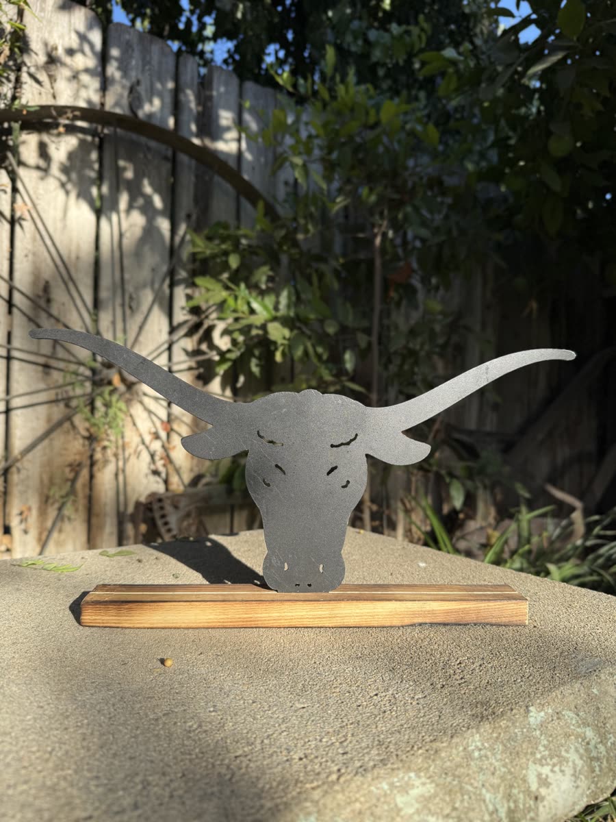 Longhorn head cut from steel on a wooden stand.