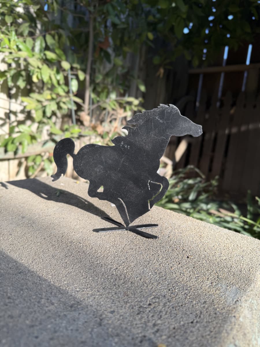 Running horse cut from steel, standing on concrete.