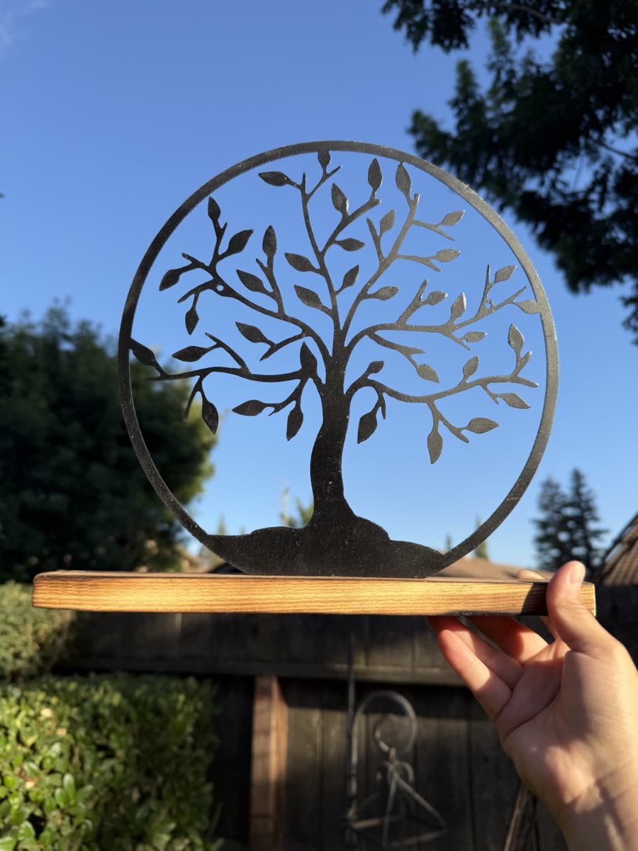 A tree with fine cut leaves inside a steel ring.