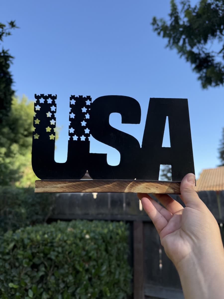 The letters USA cut from steel with stars and stripes inside them.