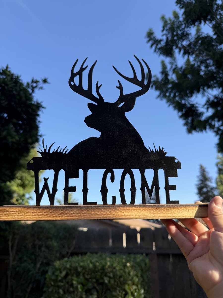Steel buck standing over the word Welcome, held against the sky.