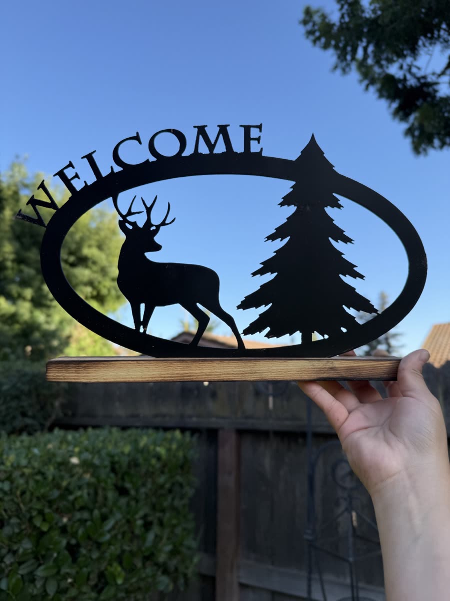 Buck and pine tree inside an oval above the word Welcome.