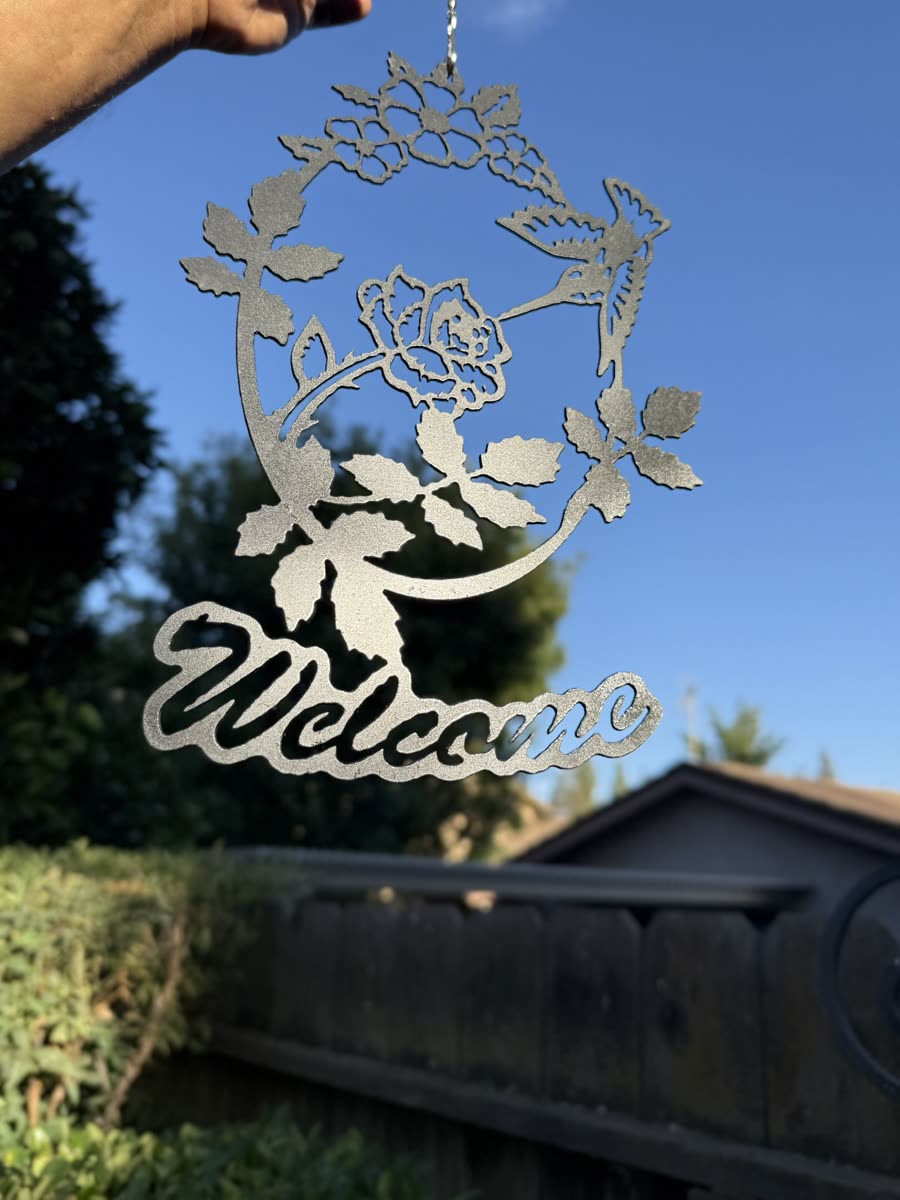 Roses and leaves above the word Welcome in script, cut from steel.