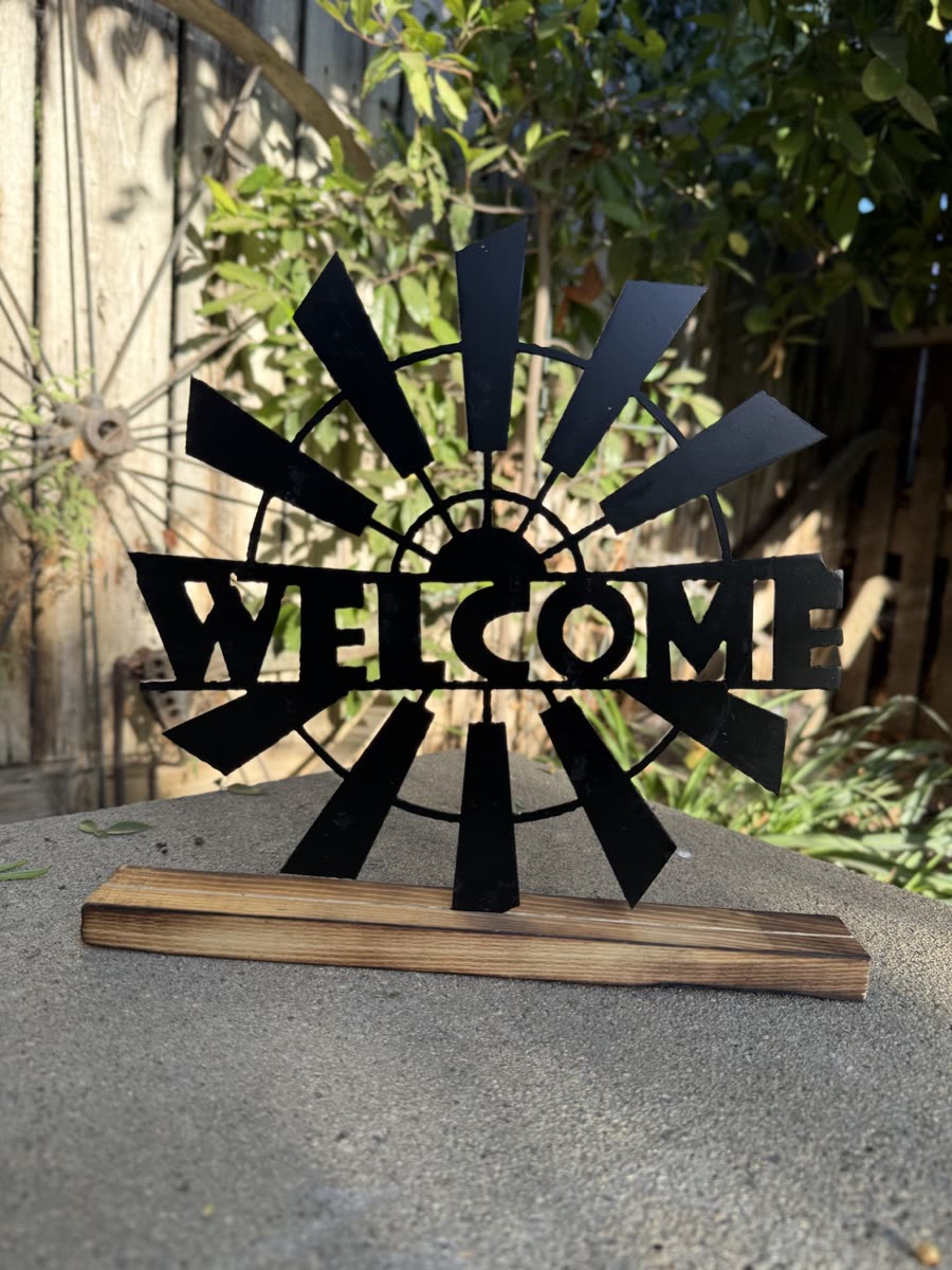 A windmill behind the word Welcome, cut from steel.