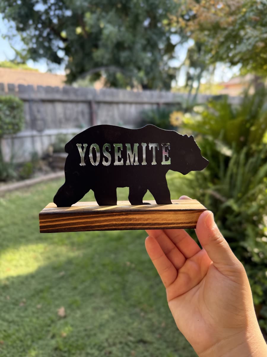 Bear with the word Yosemite cut through it, on a wooden stand.